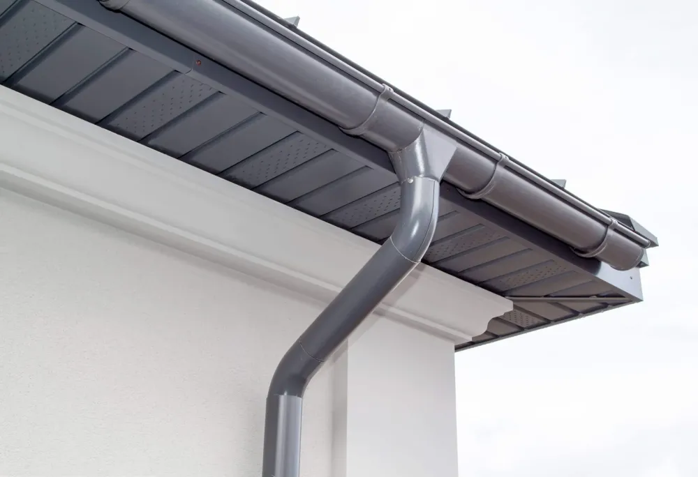 New grey gutter and downpipe on a white house
